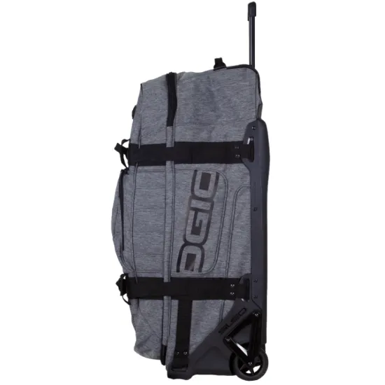 Сив меланжов сак OGIO RIG 9800 Dark Static с черна телескопична дръжка, големи колела и множество джобове, показан отворен с червена вътрешност и мотоекипировка вътре