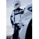 Бяло мото яке ICON Merc3 ANOMALY с черни графични елементи, носено от мотоциклетист с бяла каска седнал на бял мотор