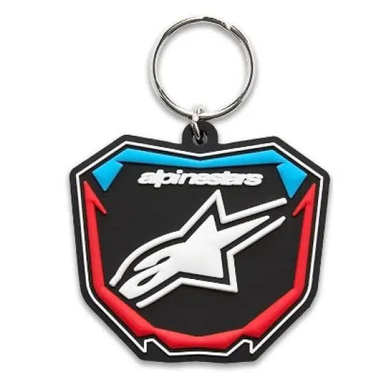 Ключодържател Alpinestars във форма на щит с черна основа, синьо-червени акценти и бяло лого на звезда, монтиран на сребрист метален пръстен