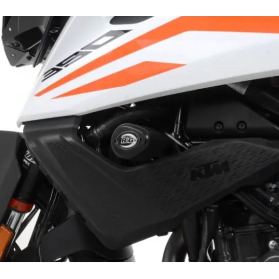 Оранжеви R&G Racing Aero краш тапи монтирани на бяло-оранжев KTM 390 Adventure мотоциклет, с видим R&G лого и черна защитна решетка
