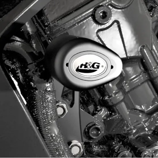 Черни краш тапи R&G Racing с овален дизайн и лого, монтирани на сребрист мотоциклетен двигател с видими болтове и метални части