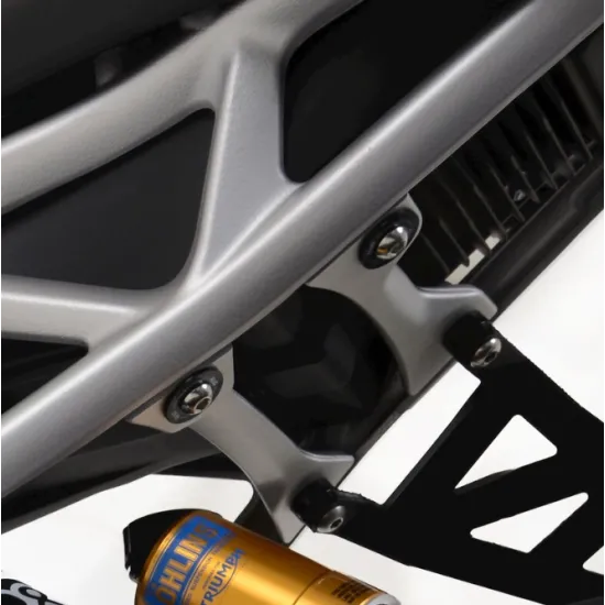 Черна R&G Racing плоча монтирана в сребристата алуминиева решетъчна подрамка на Triumph Speed Triple 1200 RS, с видими болтове и златист Öhlins амортисьор