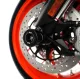 Черни CNC алуминиеви краш тапи R&G Racing монтирани на предната ост на оранжев мотоциклет с двойни дискови спирачки