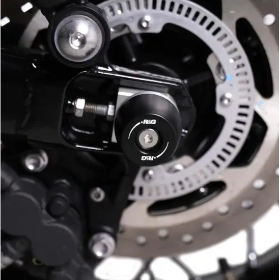 Черни краш тапи R&G Racing монтирани на задната ос на суингарм Triumph, с HDPE ролка и централен болт от неръждаема стомана